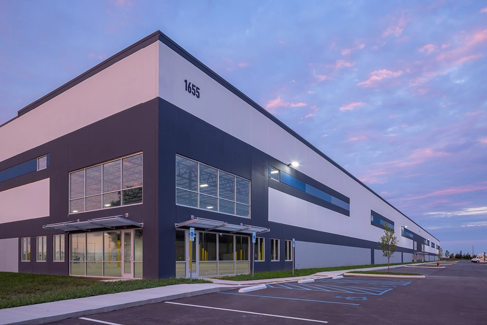 Front corner entrance of a speculative industrial building at dusk with blue and purple clouds in the sky